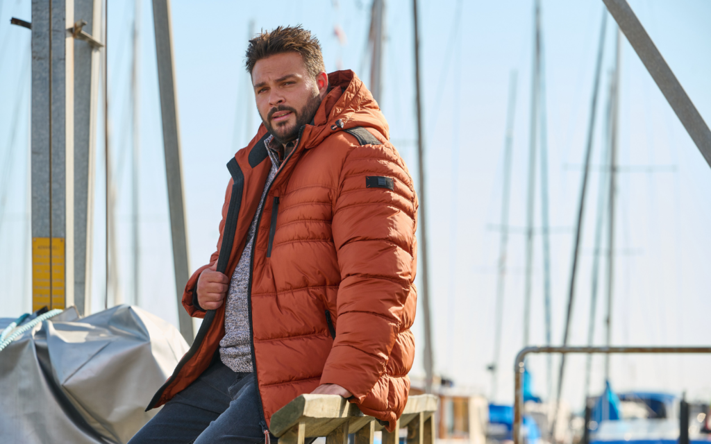 Mann in Winterjacke an einem Hafen