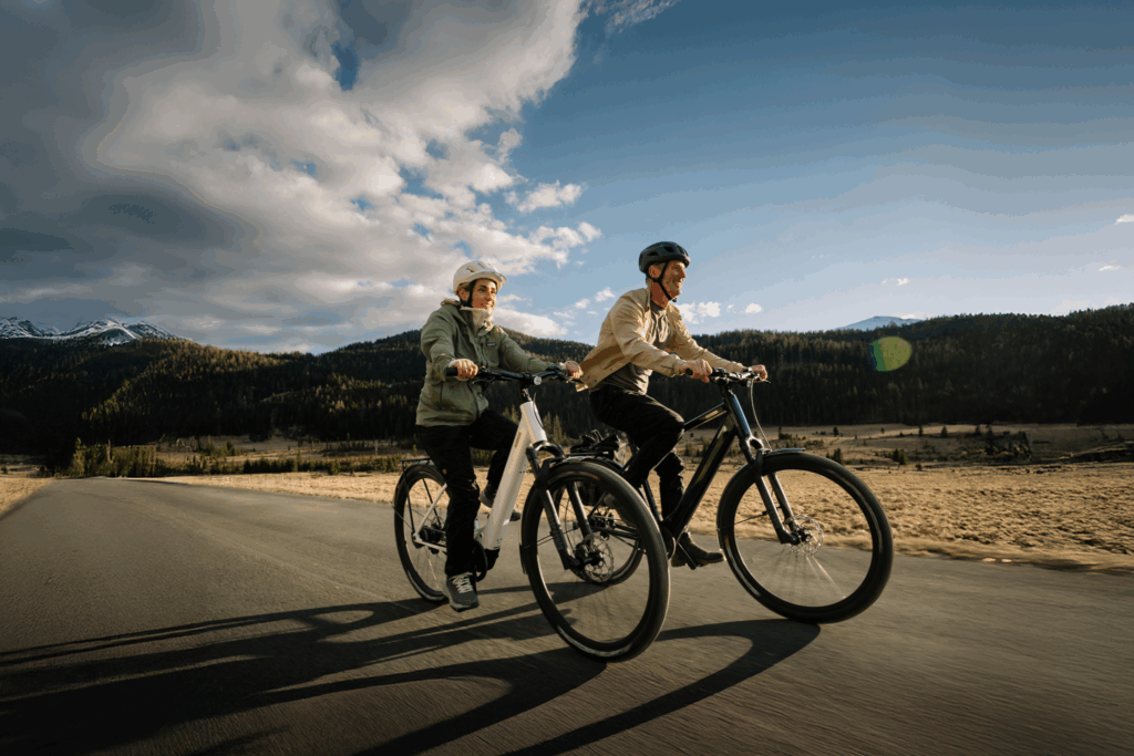 Gemeinsam unterwegs in der Natur Zwei Radfahrer genießen eine Fahrt auf einer offenen Straße vor einer beeindruckenden Berglandschaft mit ihren coboc E-Bikes.