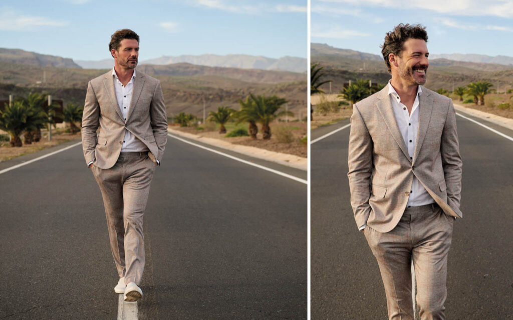 Mann trägt beigen Anzug und läuft auf einer Straße in warmer Landschaf