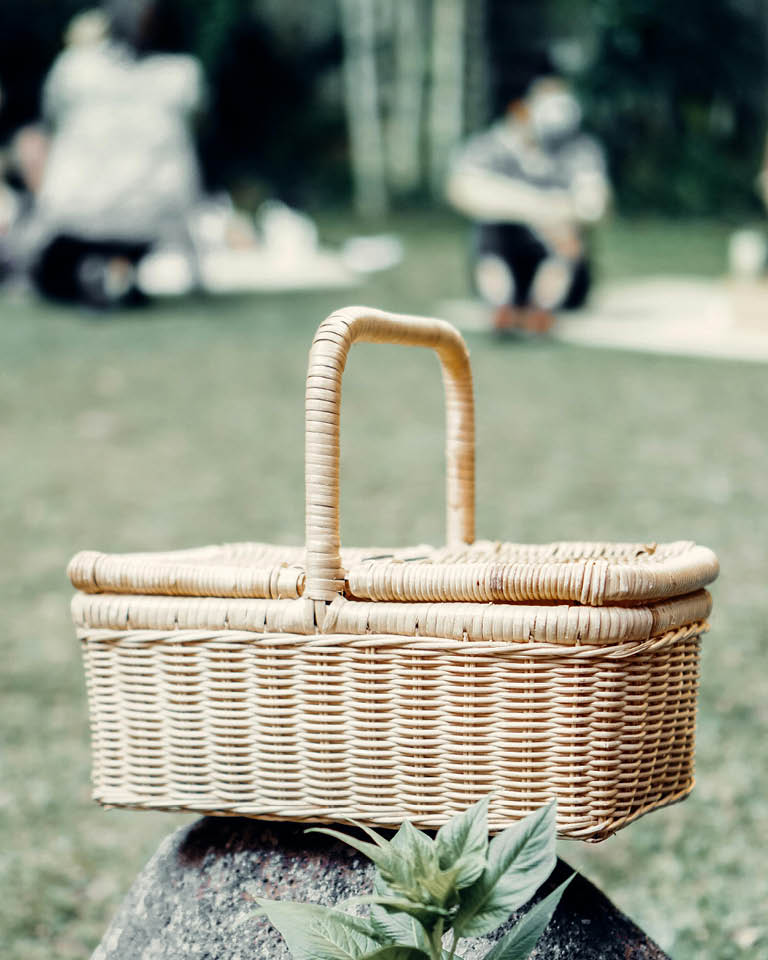 Ein geflochtener Picknickkorb steht auf einer Wiese im Freien
