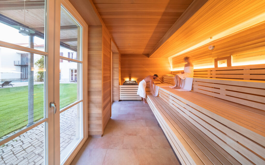 Sauna Bild Links ist eine Sauna mit Holzverkleidung und Sitzbänken zu sehen.